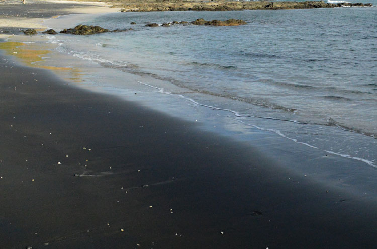 The black sand of Playa Carbón is reveals the volcanic origin of the surrounding rocks